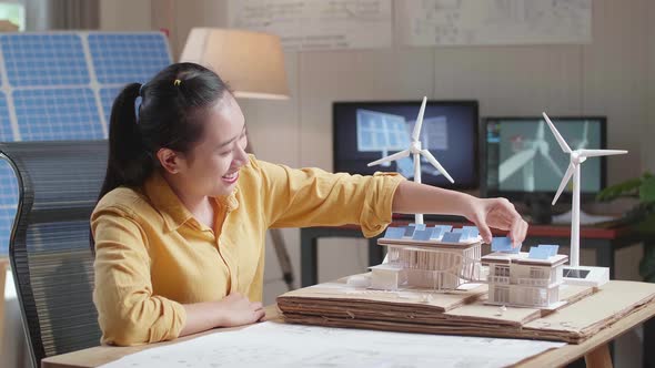 Side View Of Asian Woman Being Happy Succeed Building A Model Of Small House With Solar Panel