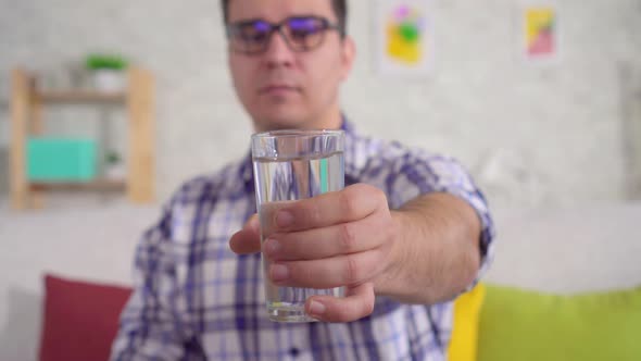 Shaking Hands of a Man Holding a Glass of Water