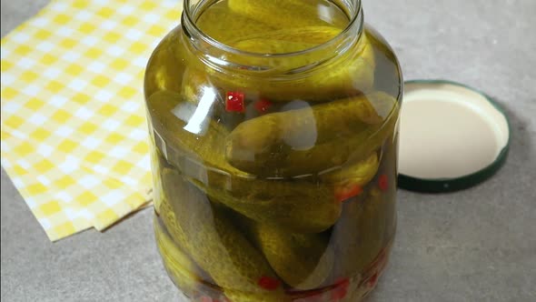 Picking a pickled cucumber from a large jar  