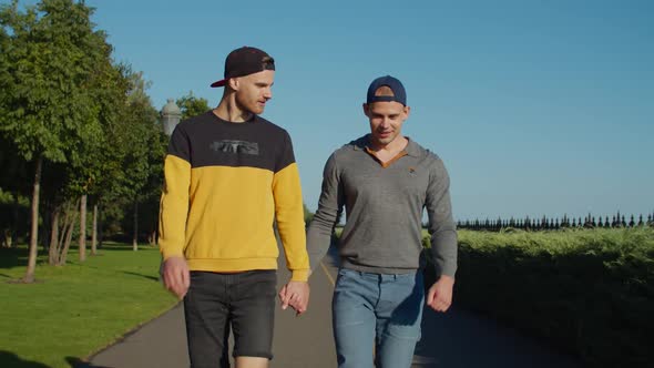Chatting Gay Couple Taking Leisurely Walk in Park