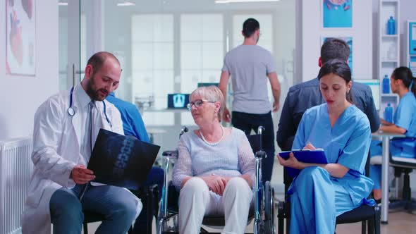 Doctor Holding Radiography of Disabled Senior Woman in Wheelchair