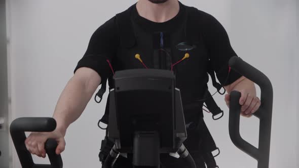 Handsome Man Wearing Electrostimulation Suit and Training on Exercise Bike