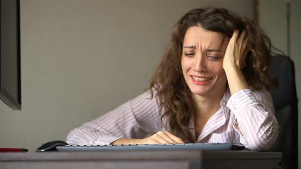 Tired Young Woman with Curly Hair and White Shirt is Working at the Office Using Her Laptop Routine