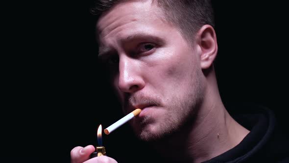Confident Gangster Lighting Cigarette and Looking at Camera, Dark Background