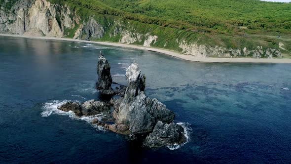 Aerial Tilt View of High Sea Stacks High Rocky Cliff Pillars and Transparent Turquoise Sea Waters