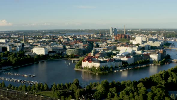 Slow aerial pan of the Helsinki waterfront reflecting on the water below at sunset, Finland.