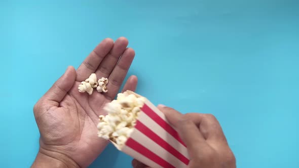 Top View of Man Eating Popcorn on Blue Background