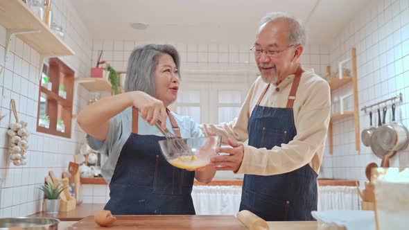 Asian happy senior older couple enjoy retirement life, cooking foods together in the kitchen at home