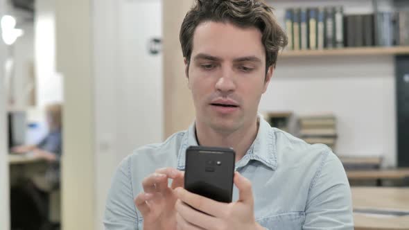 Creative Man Excited for Success While Using Smartphone