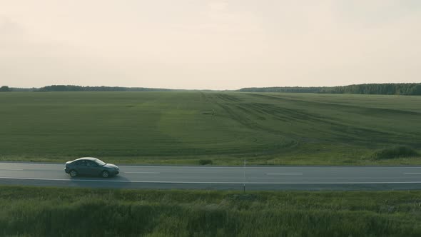 Aerial View of a Car Driving on the Road in a Field