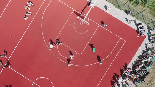 A Topdown Aerial View of Boys Playing Basketball on an Outdoor Public Basketball Court