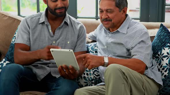 Father and son using digital tablet in living room 4k