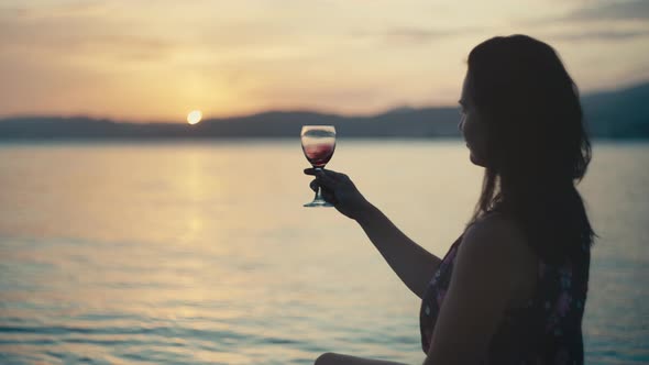 Girl with a Glass of Wine at Sunset By the Sea