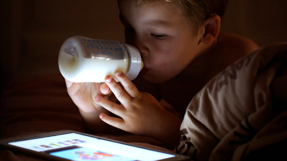 Boy Drinking Milk Looking At Touchpad