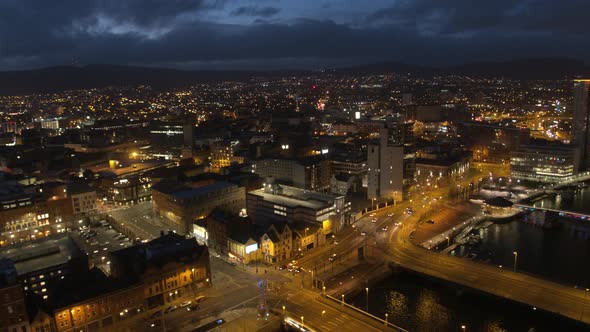 Aerial flyover of Belfast City Centre and Lagan River at night