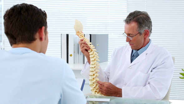 Mature Doctor Talking To His Patient About Spine