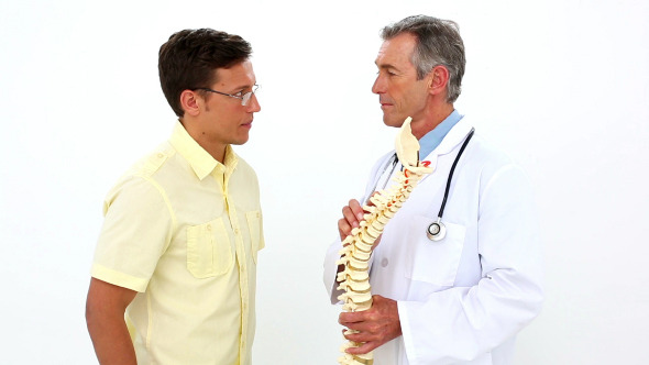 Doctor Holding Model Of Spine Talking To Patient alt