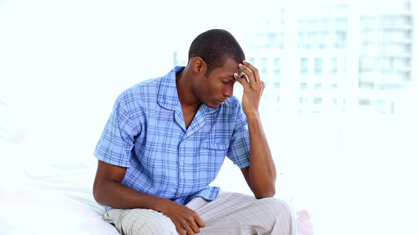 Hungover Man Sitting On The End Of His Bed