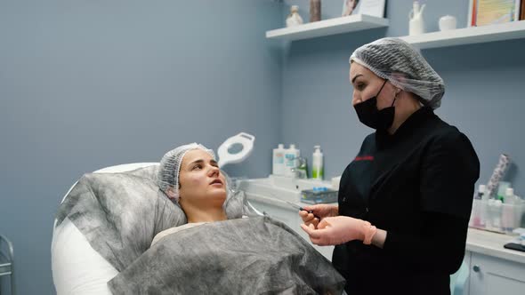 Doctor Cosmetologist Explains to Young Woman Before Cosmetic Injection with Hyaluronic Acid