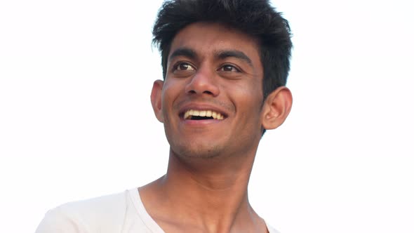 Portrait of young Sri Lankan man standing in front of white background and smiling his heart out to