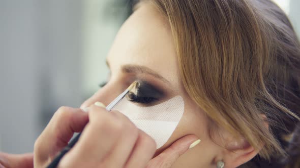 Closeup View of Makeup Artist Applying Eyeshadow on Eyelid Using Makeup Brush and Protecting Sking