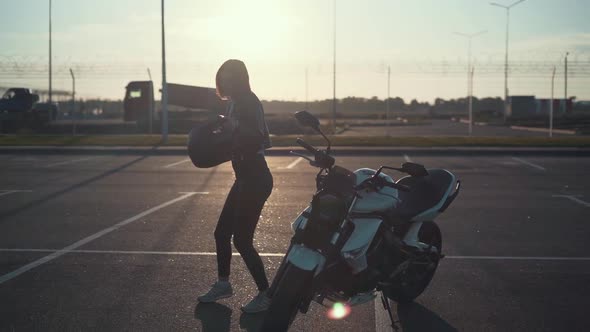 Beautiful Young Redhaired Woman Motorcyclist Dancing Next to Her Custom Bike with Black Motorcycle