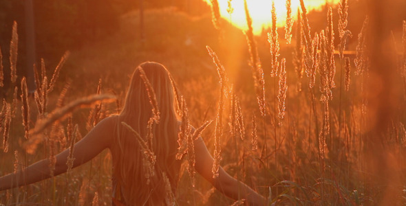 Girl Walking in a Field at Sunset