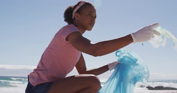 African american woman collecting plastic waste on the beach
