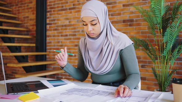 Portrait of Beautiful Muslim Woman Designer with Hijab Holding Pencil and Working on the Drawings