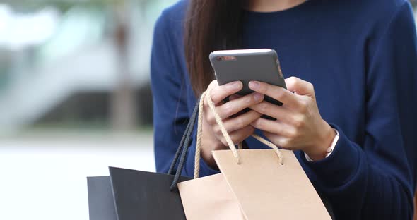 Woman use of smart phone and holding shopping bag