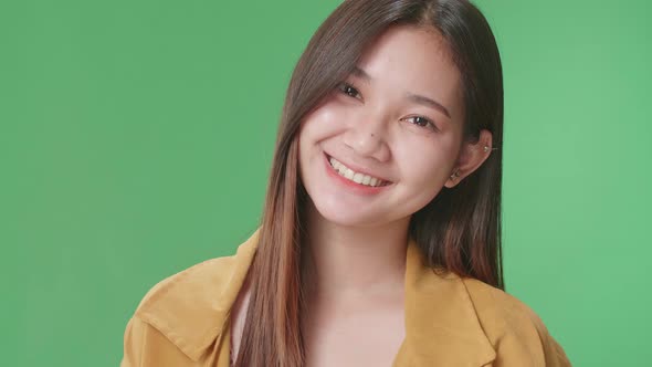 Close Up Of Young Asian Woman Warmly Smiling On Green Screen Background In The Studio