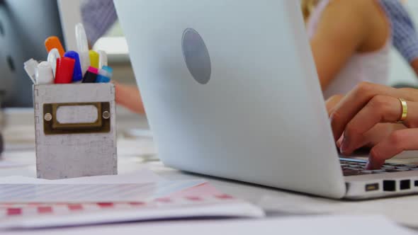 Close-up of executive using laptop at desk