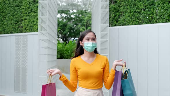 Asian woman wearing face mask. Happy woman with shopping bags