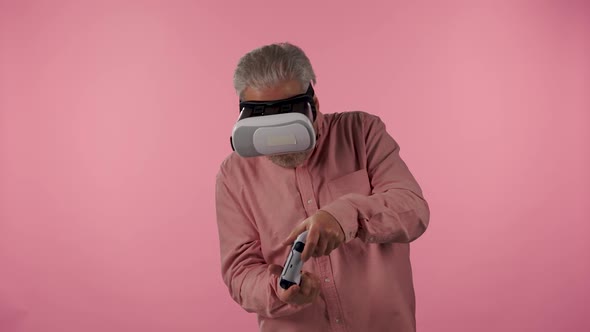 Portrait of Elderly Man with Virtual Reality Headset Playing Video Game Using Wireless Controller