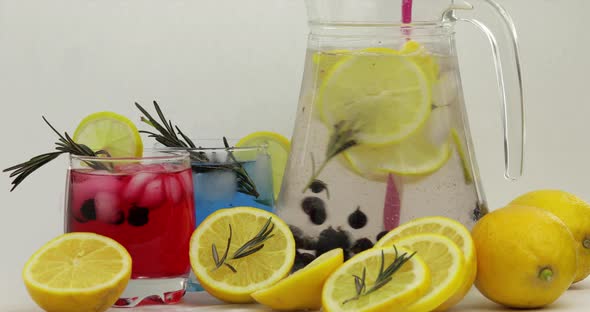 Stir of Cold Drink with Lemon, Ice Cubes and Black Currant in a Jar Glass