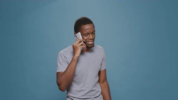 Millennial Man Talking on Smartphone Call Over Blue Background