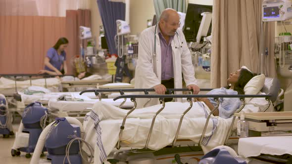 Wide shot of a Doctor looking over a patient with a pen light in hospital.