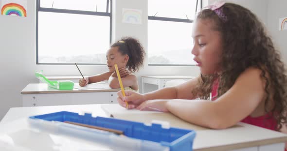 Video of biracial girls sitting at school desks and learning