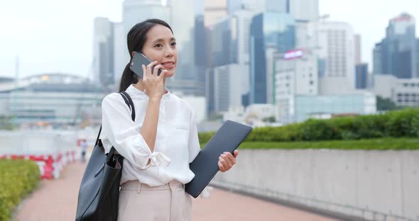 Businesswoman talk to mobile phone and hold with laptop computer