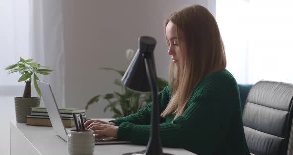 Young Woman Is Working Alone in Big Offices at Daytime Typing Text on Keyboard of Modern Laptop with