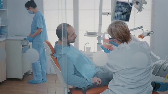 Dentist Giving Hygiene Lesson to Patient to Clean Teeth Correctly