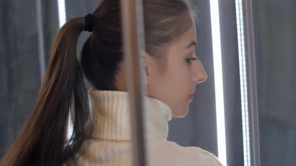 Young Woman with Ponytail Looks at Shower Cabin Close