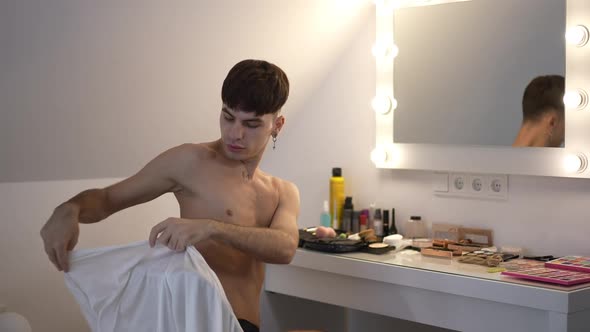 Young Millennial Caucasian Woman Sitting on Chair in Front of Mirror and Cosmetics Putting on Silk