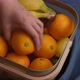 A woman putting her hand into a basket of fruit and pulling out an orange. - VideoHive Item for Sale