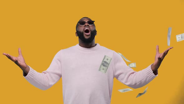 Happy AfricanAmerican Man Throwing Dollars Banknotes Wasting Money on Yellow Background