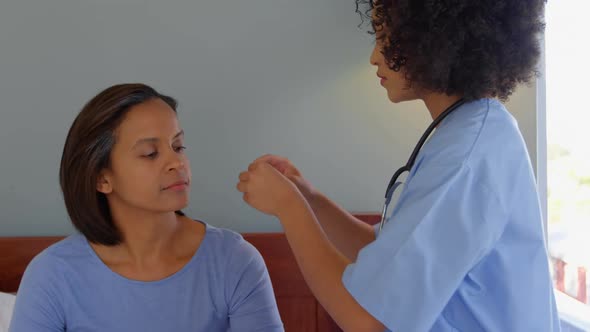 Mixed race female doctor inserting a hearing aid machine on womans ear at home 4k