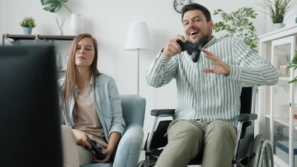 Disabled Man Playing Videogame with Girlfriend Winning Dancing in Wheelchair at Home
