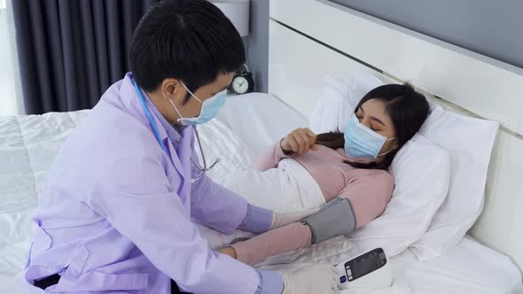 doctor measuring blood pressure of sick woman in bed