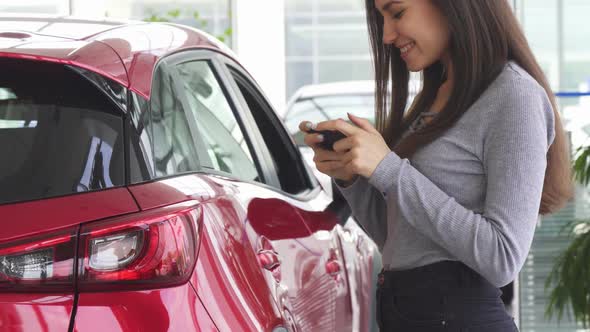 Cropped Shot of a Woman Using Her Smart Phone Standing near Her Car