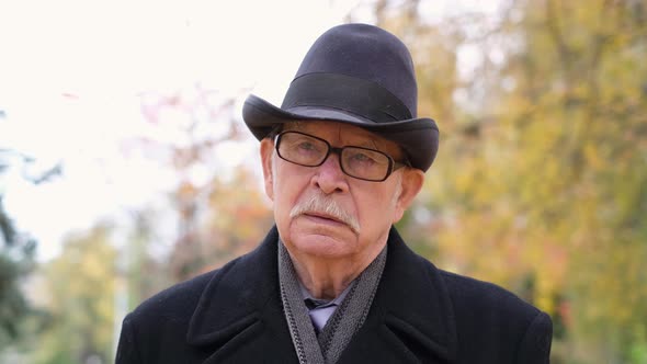 Lonely Grandfather in the Park Dressed in a Black Coat and Black Hat